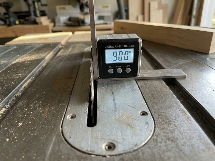 Digital angle gauge placed against table saw blade face showing 90 degree reading